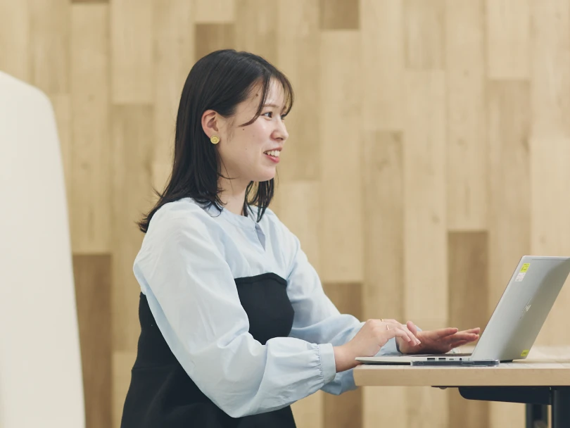 ノートPCを使いながら笑顔で同僚と話す女性社員