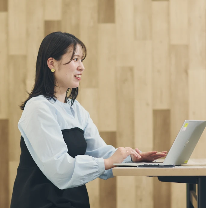 ノートPCを使いながら笑顔で同僚と話す女性社員