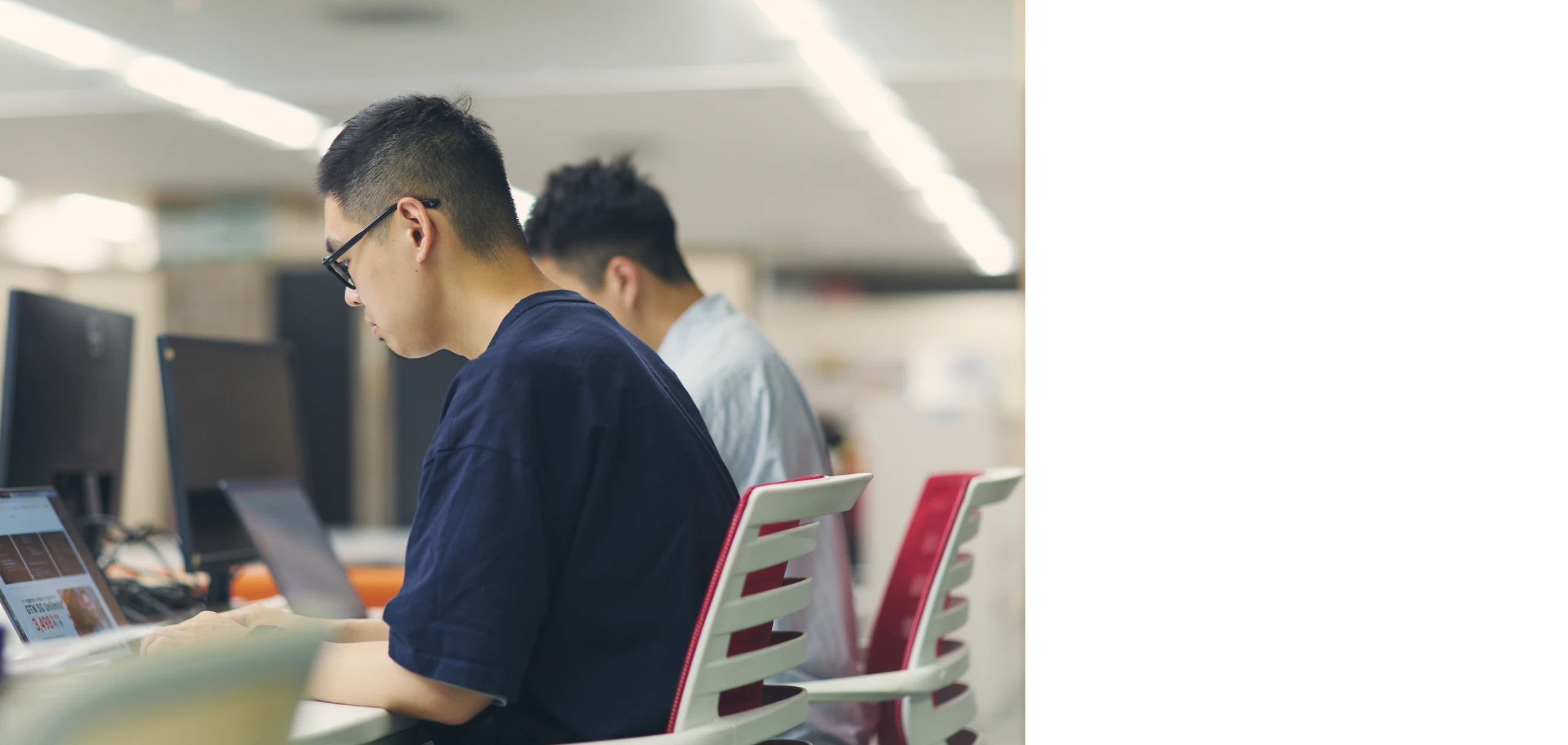 オフィスでモニターに向かって集中して作業する男性社員2人