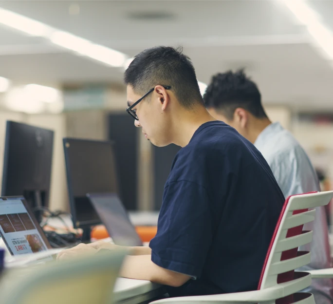 オフィスでモニターに向かって集中して作業する男性社員2人