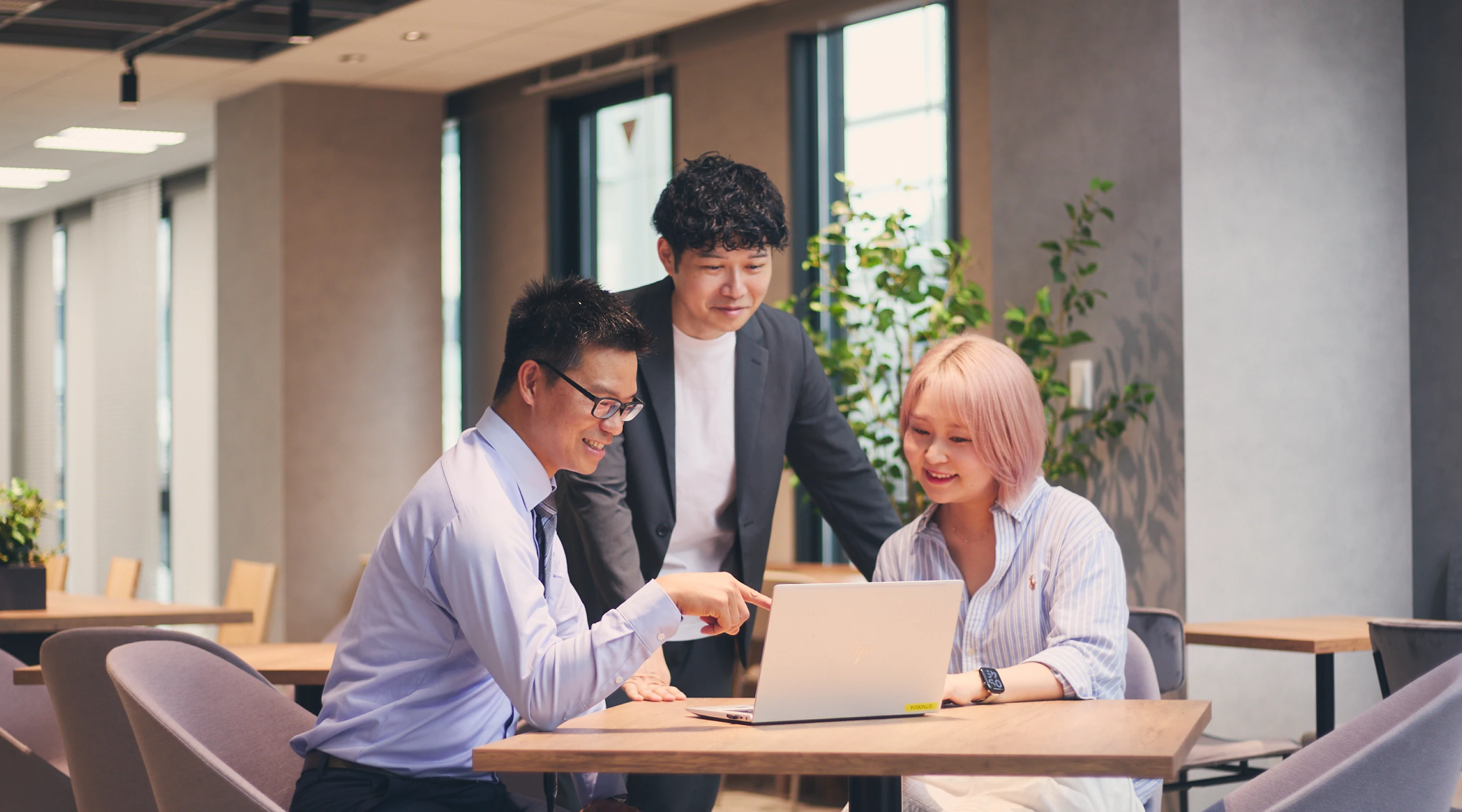 ノートPCの画面を指さしながら打ち合わせをする3人の社員