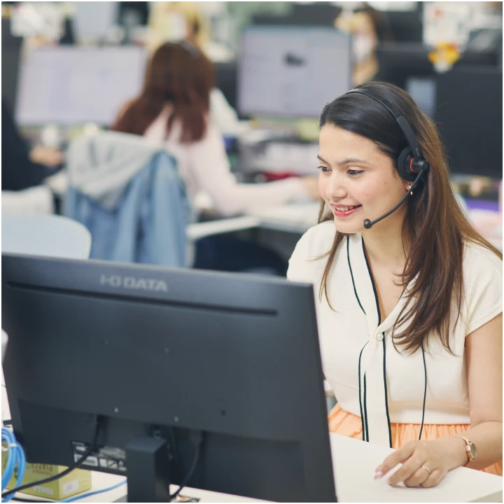 ヘッドセットを装着し笑顔で業務に取り組む女性社員