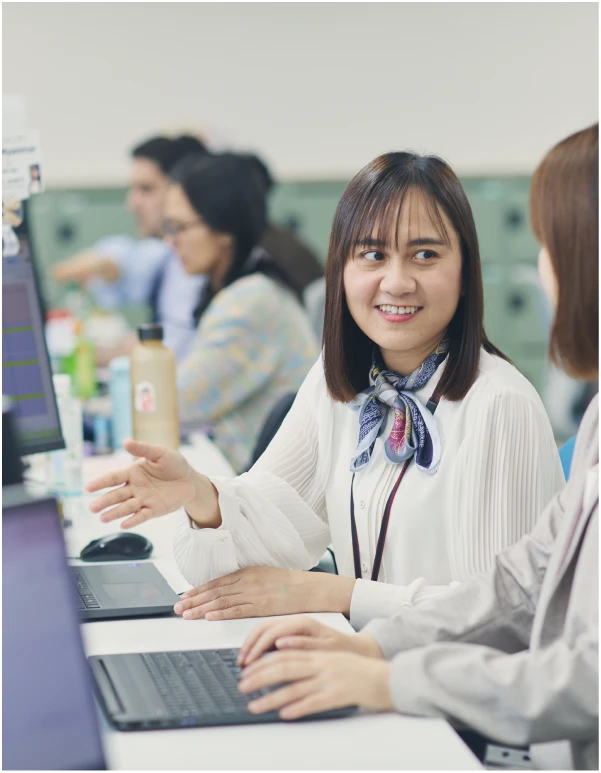 笑顔で同僚と話す赤いストラップを下げた女性社員