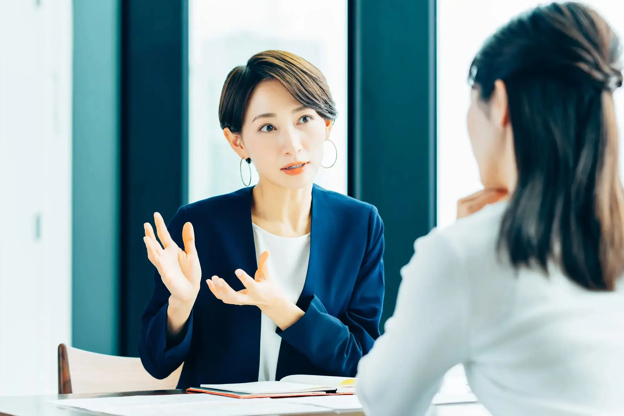 女性がパソコンを見ながら電話している画像